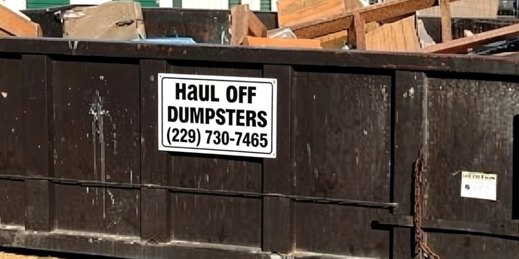 A Haul Off Dumpsters roll-off container loaded with building debris, photographed side-on